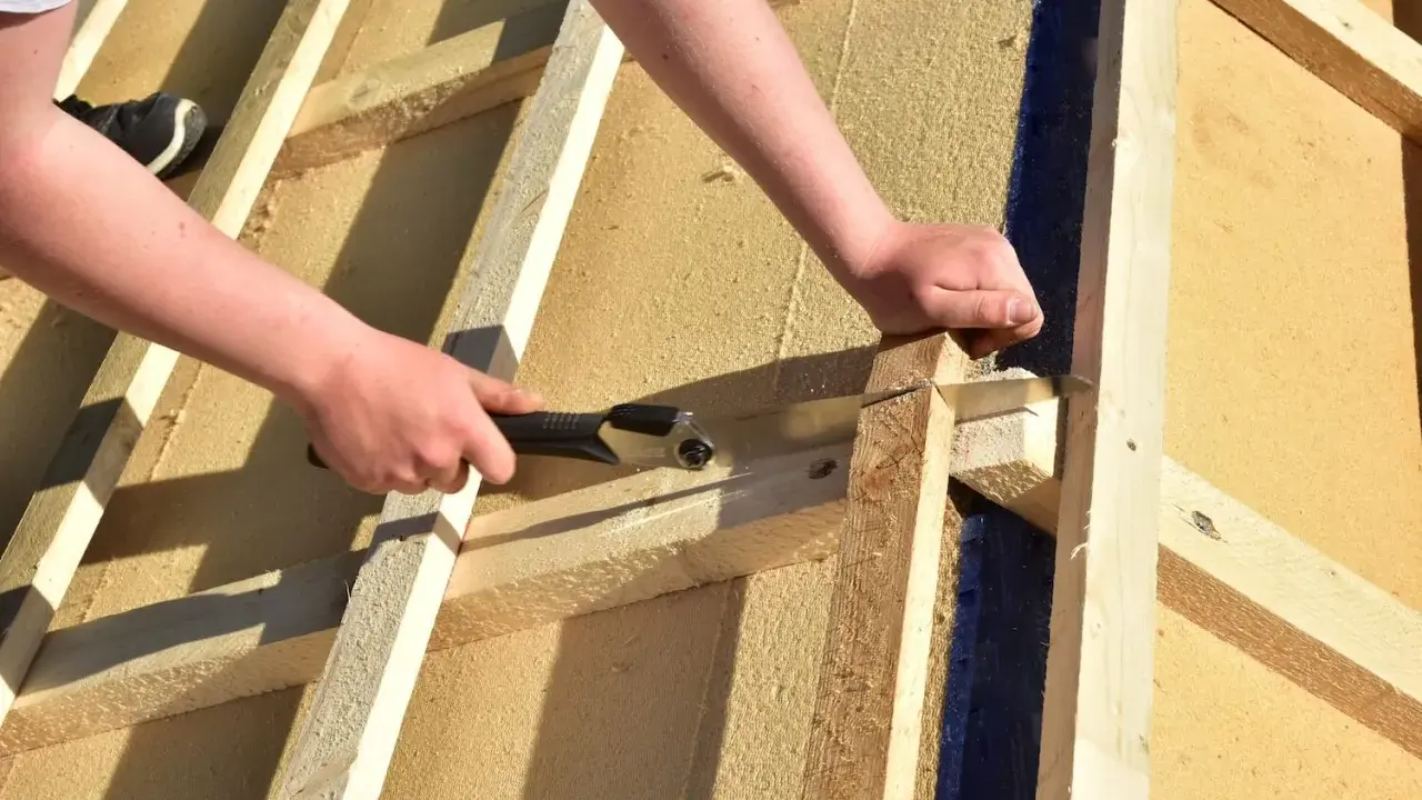 Holzfaserplatte Fassade: Hände sägen Holz für den Hausbau.