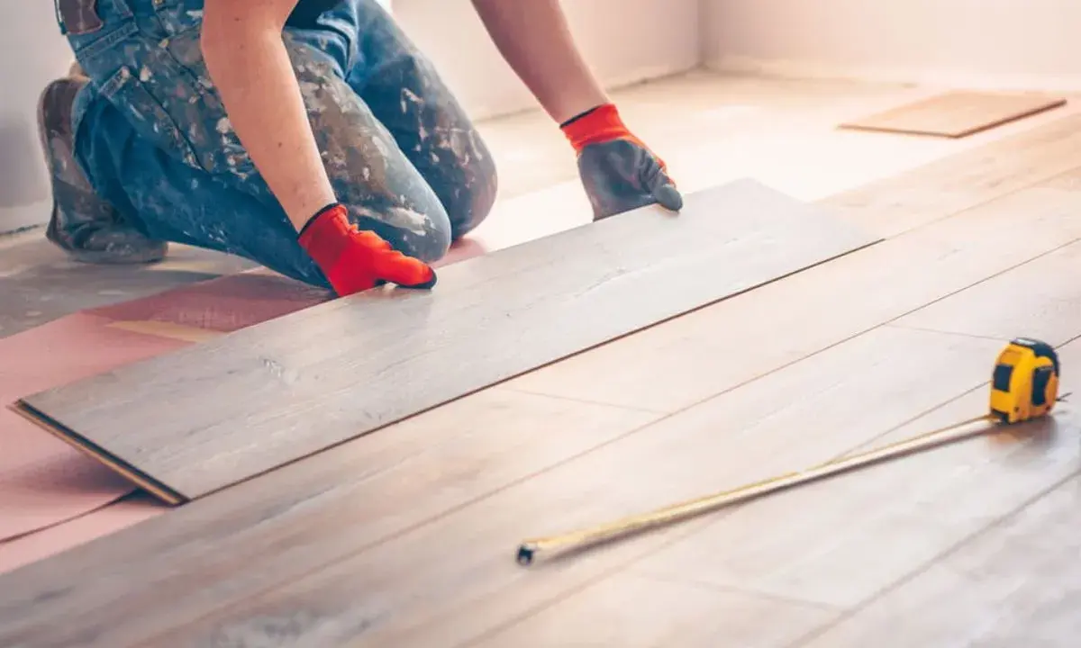 Handwerker verlegt Laminat. Eine Dehnungsfuge ist wichtig, damit sich das Holz ausdehnen kann.