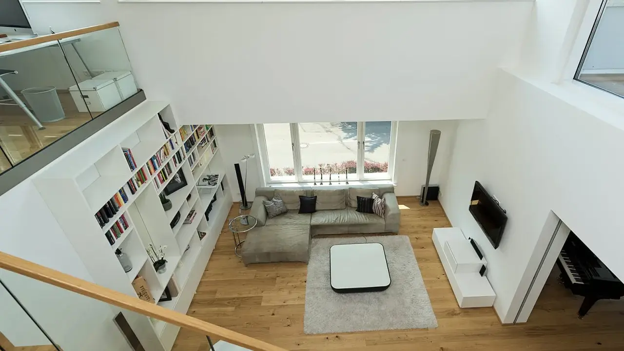 Ein offener Wohnbereich mit viel Licht und Raum. Die moderne luftraum architektur mit großen Fenstern und einer offenen Treppe schafft ein Gefühl von Weite.