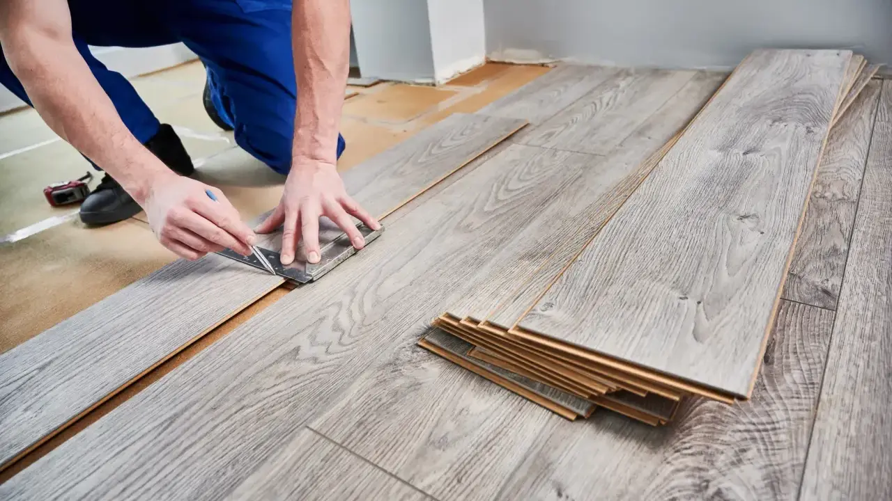 Handwerker misst Laminat für die Verlegung. Die Kosten für Laminat verlegen sind oft überschaubar.