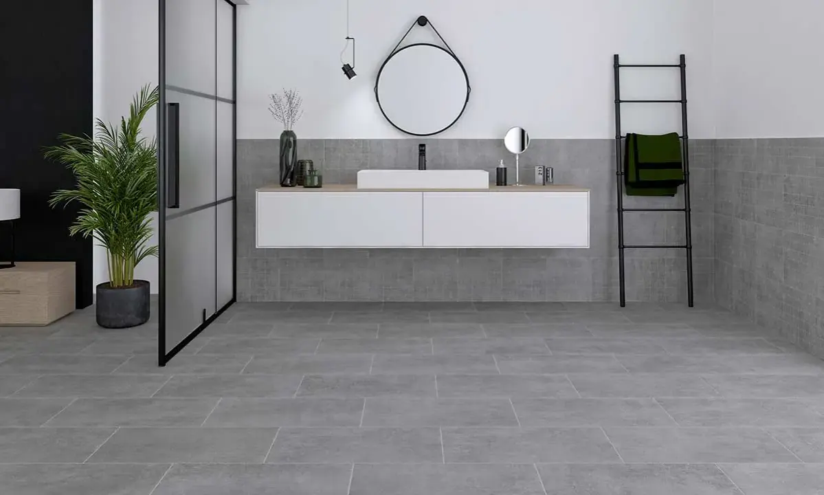 Modernes Badezimmer mit grauen Bodenfliesen und Wandfliesen, die das Ambiente von fliesen sanieren unterstreichen. Ein schwebendes Waschbecken und eine Glasdusche runden das Bild ab.
