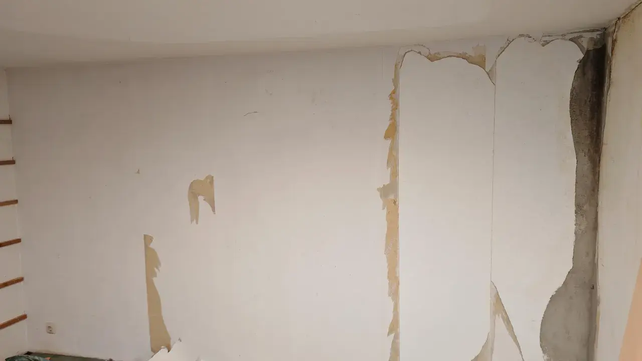 Renovierungsarbeiten: Alte Tapete wird entfernt, um die Wand für neues **Styropor tapezieren** vorzubereiten.