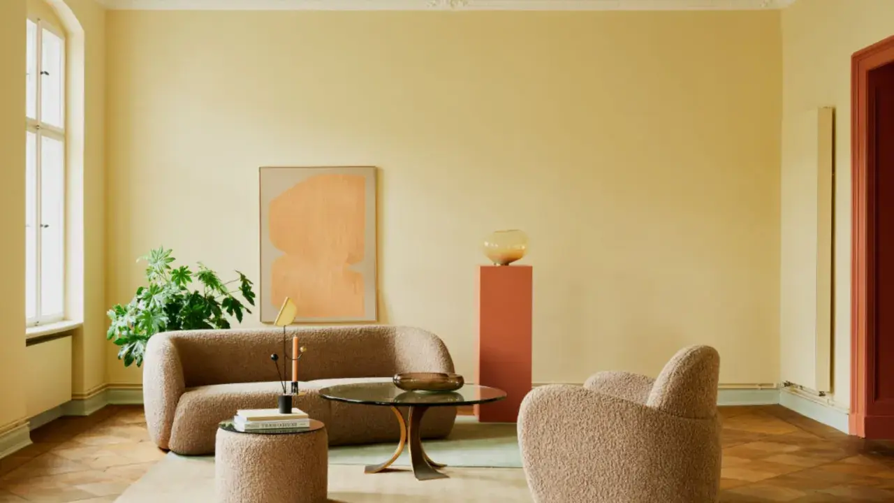Ein Wohnzimmer mit gelben Wänden und einem frisch gestrichenen, hellgrünen Decke. Gemütliche Bouclé-Möbel und ein moderner Couchtisch laden zum Verweilen ein.
