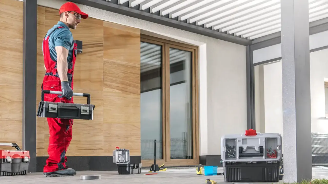 Handwerker mit Werkzeugkasten bereitet sich auf das vordach abdichten vor. Werkzeuge und Materialien liegen bereit.