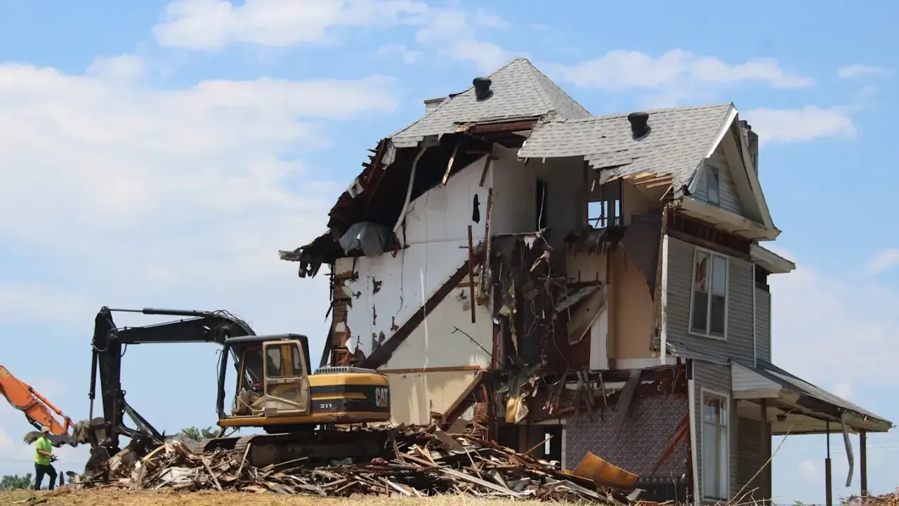 Bagger reißt ein Haus ab. Die Abrisskosten für dieses Haus sind hoch, da es stark beschädigt ist.
