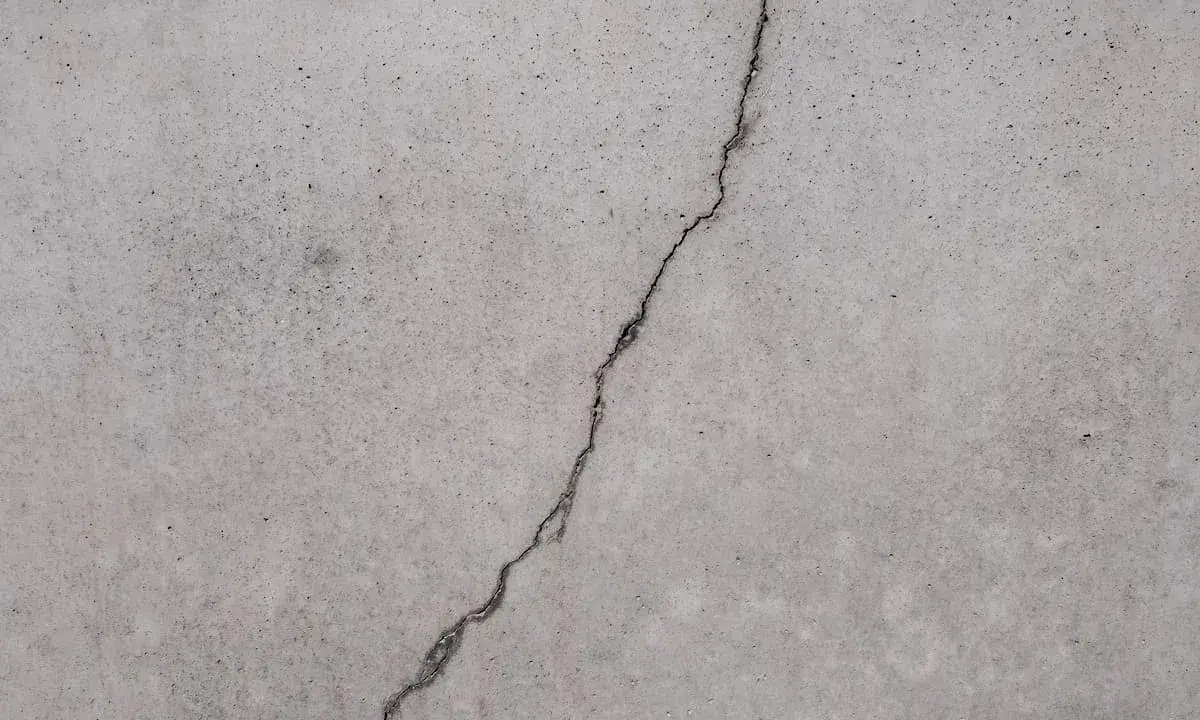 Ein Riss im Betonboden zeigt die Notwendigkeit, den Estrich reparieren zu lassen, um weitere Schäden zu vermeiden.
