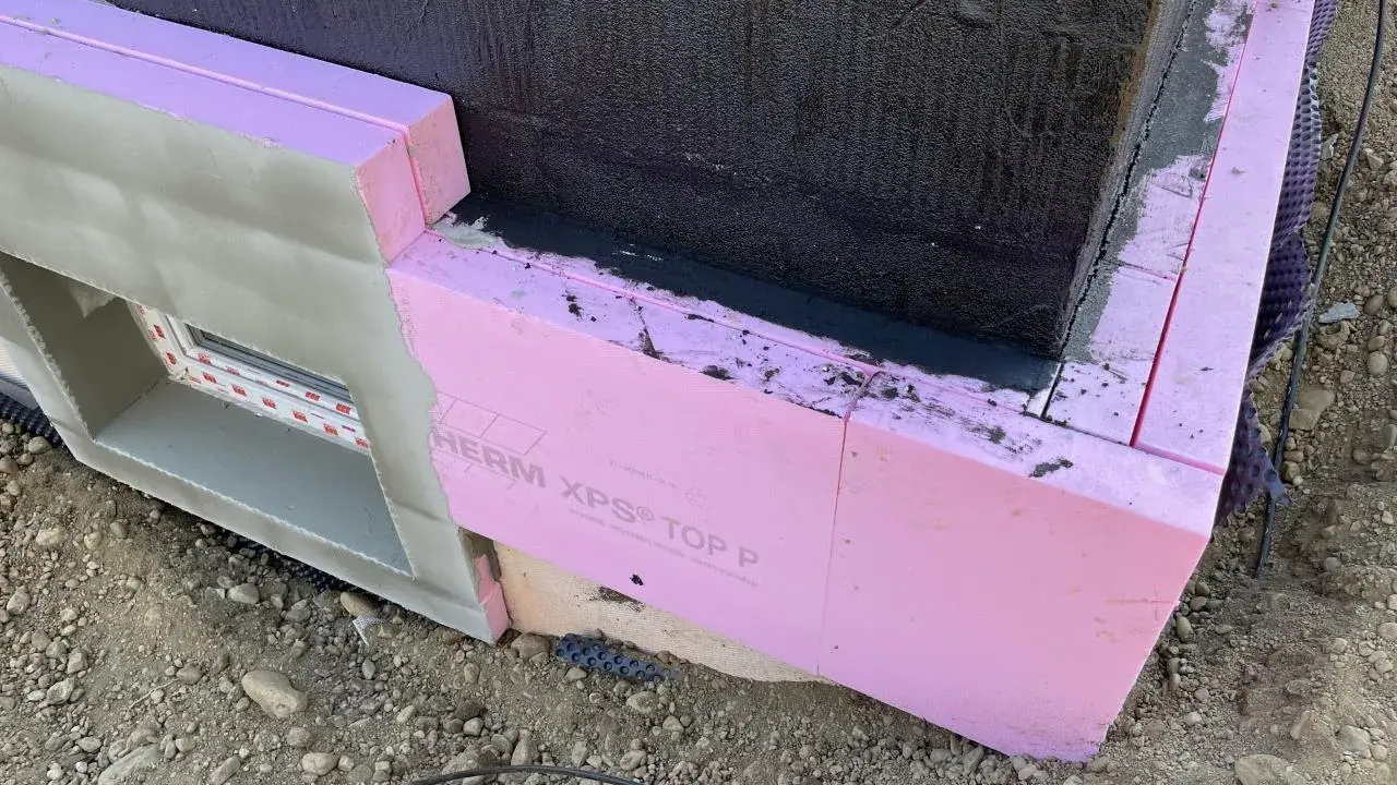 Dämmung wird angebracht. Pinke Styrodurplatten werden sorgfältig an die Wand geklebt, um das Gebäude zu isolieren.