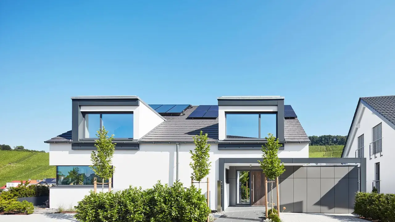 Moderner Hausbau mit Solaranlagen auf dem Dach. Ein Architekt hat hier ein stilvolles Einfamilienhaus mit Garage und gepflegtem Garten entworfen.