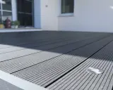 Moderne Terrasse mit grauen WPC Terrassendielen verlegen. Ein kleiner Bodenspot ist bereits integriert.