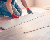 Handwerker verlegt Laminat. Eine Dehnungsfuge ist wichtig, damit sich das Holz ausdehnen kann.
