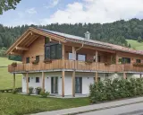 Ein modernes Holzhaus mit Balkonen und Blick auf grüne Hügel. So könnte man beschreiben, was ein Chalet in den Bergen ist.