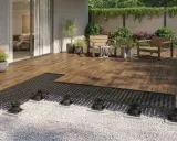 Terrassenplatten mit schwarzem Unterbau auf Kiesbett, bereit für die Montage. Ein moderner Aufbau für eine langlebige Terrasse.