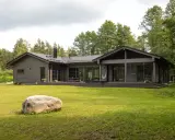 Ein modernes Architektenhaus aus Holz, eingebettet in üppiges Grün. Große Fensterfronten und eine Terrasse laden zum Entspannen ein.