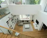 Ein offener Wohnbereich mit viel Licht und Raum. Die moderne luftraum architektur mit großen Fenstern und einer offenen Treppe schafft ein Gefühl von Weite.