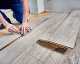 Handwerker misst Laminat für die Verlegung. Die Kosten für Laminat verlegen sind oft überschaubar.
