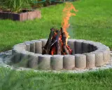 Eine Feuerstelle mit gemauerten Steinen und loderndem Feuer im Garten.