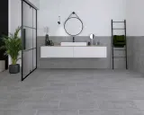 Modernes Badezimmer mit grauen Bodenfliesen und Wandfliesen, die das Ambiente von fliesen sanieren unterstreichen. Ein schwebendes Waschbecken und eine Glasdusche runden das Bild ab.