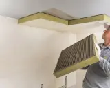 Mann mit Kleber auf Dämmplatte bereitet vor, die Decke zu isolieren.