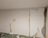 Renovierungsarbeiten: Alte Tapete wird entfernt, um die Wand für neues **Styropor tapezieren** vorzubereiten.