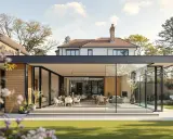 Ein modernes Haus mit Glasfronten und Holzakzenten, das auf eine gepflegte Rasenfläche blickt. Innen sind Ess- und Wohnbereiche zu sehen.