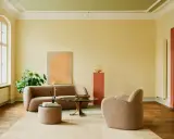 Ein Wohnzimmer mit gelben Wänden und einem frisch gestrichenen, hellgrünen Decke. Gemütliche Bouclé-Möbel und ein moderner Couchtisch laden zum Verweilen ein.