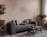 Gemütliches Wohnzimmer mit Sofa, Holztisch und rustikalen Dekorationen vor einer Wand mit **lime wash**-Oberfläche.