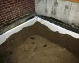 Styrodurplatten werden auf Bitumen geklebt, um eine Dämmung zu schaffen. Sand liegt auf den Platten.