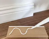 Kleber wird auf eine Sockelleiste aufgetragen, um sie an der Wand zu befestigen.