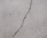 Ein Riss im Betonboden zeigt die Notwendigkeit, den Estrich reparieren zu lassen, um weitere Schäden zu vermeiden.