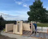 Männer bauen ein Gartenhaus. Die Montage schreitet voran, die Baugenehmigung ist hoffentlich vorhanden.
