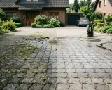 Hochdruckreiniger entfernt Moos und Unkraut von gepflasterter Einfahrt.