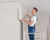 Handwerker montiert Kalziumsilikatplatten an der Decke. Mögliche Nachteile: Staubentwicklung und Bruchgefahr bei unsachgemäßer Handhabung.