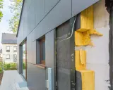 Fassade im Bau: WDVS selber machen mit gelber Steinwolle-Dämmung, die an einer grauen Verkleidung angebracht wird.