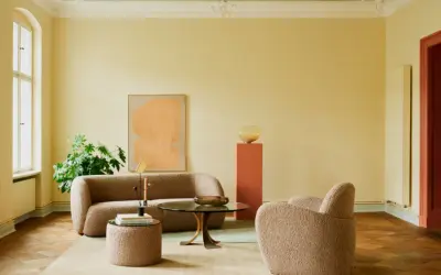 Ein Wohnzimmer mit gelben Wänden und einem frisch gestrichenen, hellgrünen Decke. Gemütliche Bouclé-Möbel und ein moderner Couchtisch laden zum Verweilen ein.