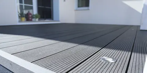 Moderne Terrasse mit grauen WPC Terrassendielen verlegen. Ein kleiner Bodenspot ist bereits integriert.