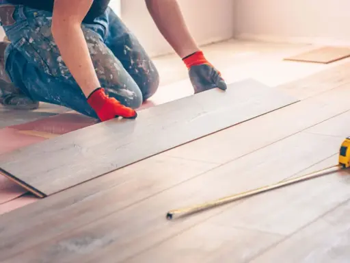 Handwerker verlegt Laminat. Eine Dehnungsfuge ist wichtig, damit sich das Holz ausdehnen kann.