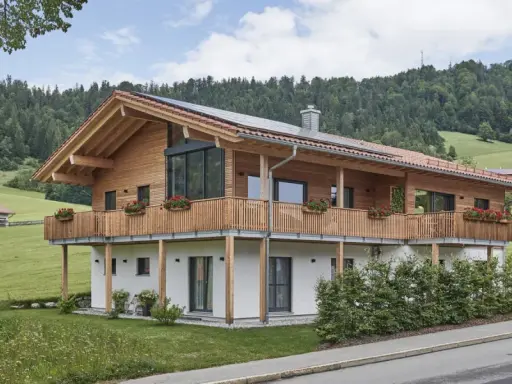 Ein modernes Holzhaus mit Balkonen und Blick auf grüne Hügel. So könnte man beschreiben, was ein Chalet in den Bergen ist.