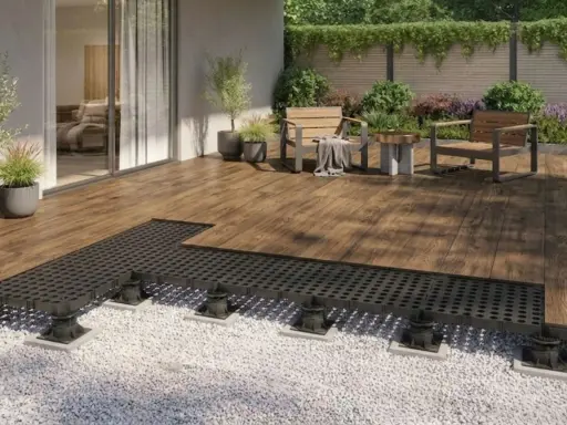 Terrassenplatten mit schwarzem Unterbau auf Kiesbett, bereit für die Montage. Ein moderner Aufbau für eine langlebige Terrasse.