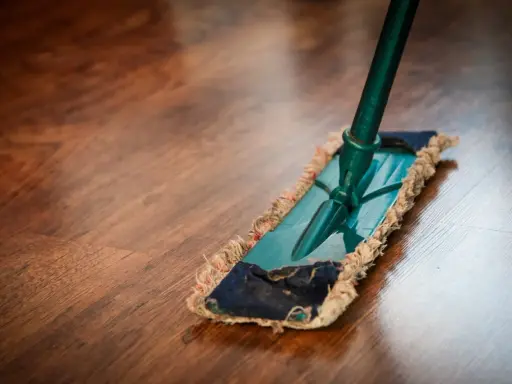 Ein Mopp reinigt einen Holzboden. Die richtige Parkett Pflege sorgt für Glanz und Langlebigkeit.