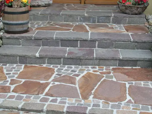 Stufen mit polygonalplatten verlegen. Große, unregelmäßige Steinplatten und kleine Pflastersteine bilden ein schönes Muster.