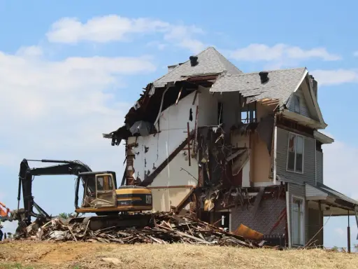 Bagger reißt ein Haus ab. Die Abrisskosten für dieses Haus sind hoch, da es stark beschädigt ist.