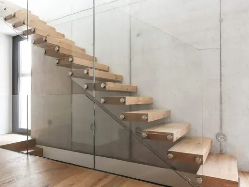Moderne Holztreppe mit Glasgeländer an Betonwand. Hier können Sie die treppe kosten berechnen.