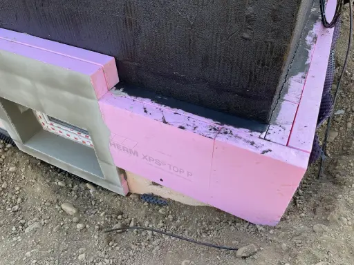 Dämmung wird angebracht. Pinke Styrodurplatten werden sorgfältig an die Wand geklebt, um das Gebäude zu isolieren.