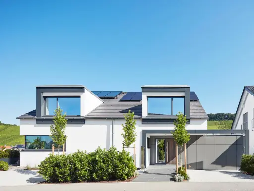 Moderner Hausbau mit Solaranlagen auf dem Dach. Ein Architekt hat hier ein stilvolles Einfamilienhaus mit Garage und gepflegtem Garten entworfen.