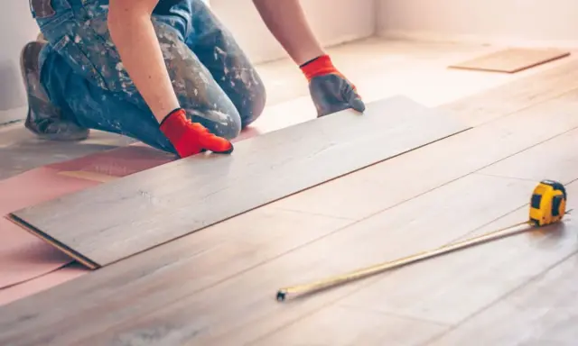 Handwerker verlegt Laminat. Eine Dehnungsfuge ist wichtig, damit sich das Holz ausdehnen kann.