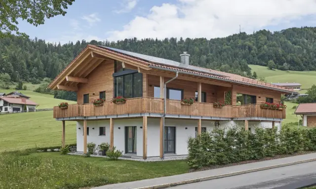 Ein modernes Holzhaus mit Balkonen und Blick auf grüne Hügel. So könnte man beschreiben, was ein Chalet in den Bergen ist.