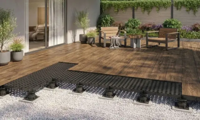 Terrassenplatten mit schwarzem Unterbau auf Kiesbett, bereit für die Montage. Ein moderner Aufbau für eine langlebige Terrasse.