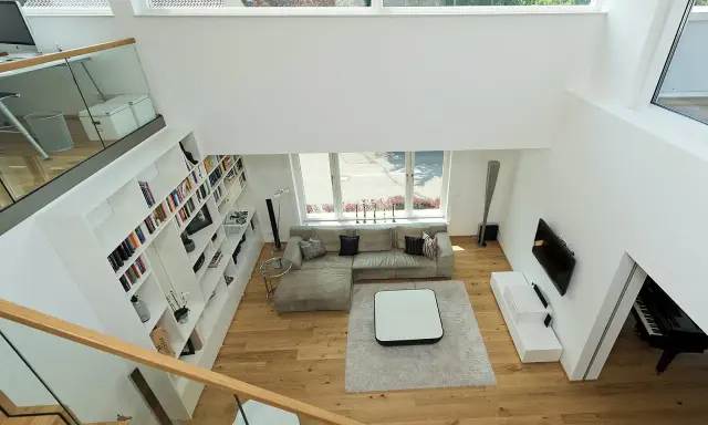 Ein offener Wohnbereich mit viel Licht und Raum. Die moderne luftraum architektur mit großen Fenstern und einer offenen Treppe schafft ein Gefühl von Weite.