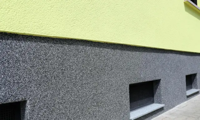 Der Sockel ist mit einem robusten, grauen Körnchenputz verputzt, der gut zu den kleinen Kellerfenstern passt.