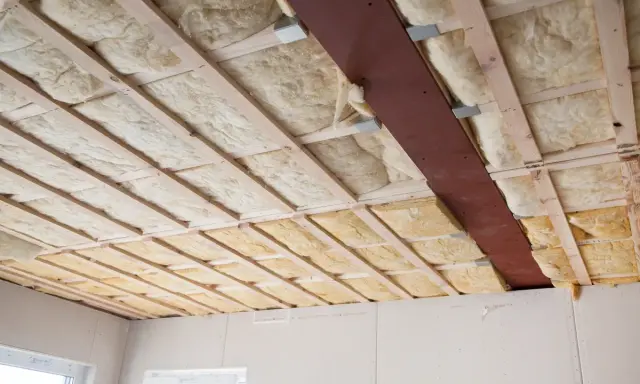 Holzlatten und eine Metallstrebe stützen die Dämmung. Glaswolle verarbeiten für eine gute Isolierung.